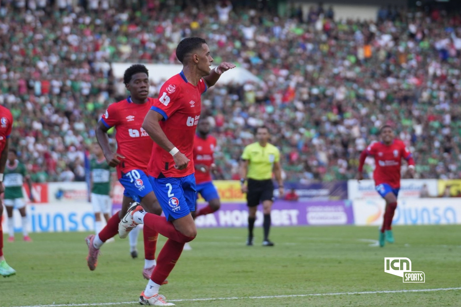  Imagen ICN Sports: Emanuel Hern&aacute;ndez celebra con determinaci&oacute;n el gol del empate de Olimpia en el estadio Ol&iacute;mpico. El defensor corre con el pu&ntilde;o en alto tras conectar de cabeza, mientras sus compa&ntilde;eros lo siguen